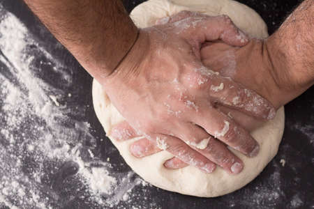 Male hands kneading dough, baking preparation closeup.の写真素材