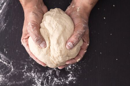 Male hands kneading dough, baking preparation closeup.の写真素材