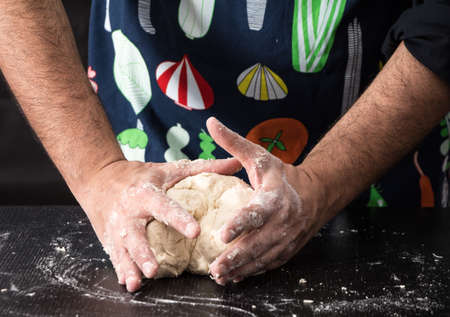 Male hands kneading dough, baking preparation closeup.の写真素材