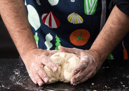 Male hands kneading dough, baking preparation closeup.の写真素材