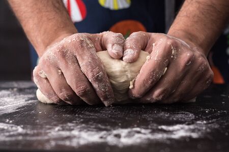 Male hands kneading dough, baking preparation closeup.の写真素材