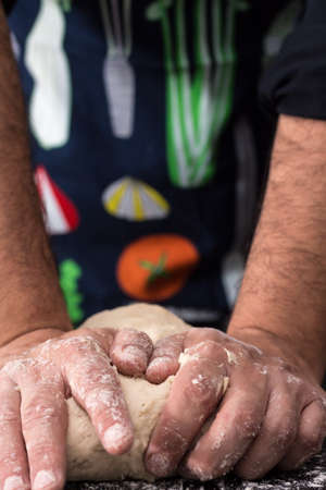 Male hands kneading dough, baking preparation closeup.の写真素材