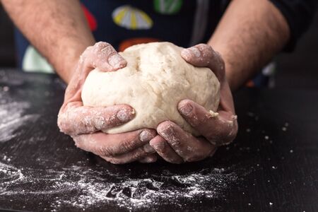 Male hands kneading dough, baking preparation closeup.の写真素材