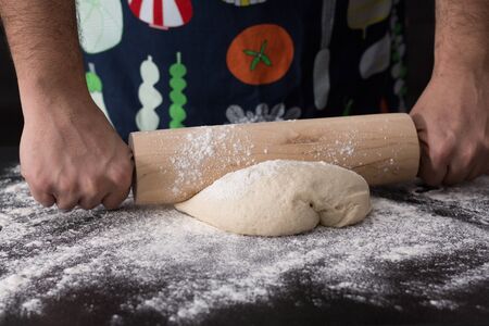 Male hands rolling dough, baking preparation closeup.