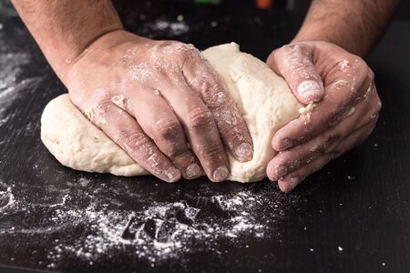 Male hands kneading dough, baking preparation closeup.の写真素材