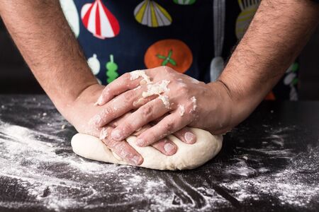 Male hands kneading dough, baking preparation closeup.の写真素材