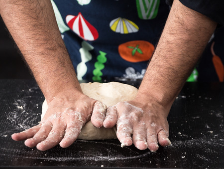 Male hands kneading dough, baking preparation closeup.の写真素材