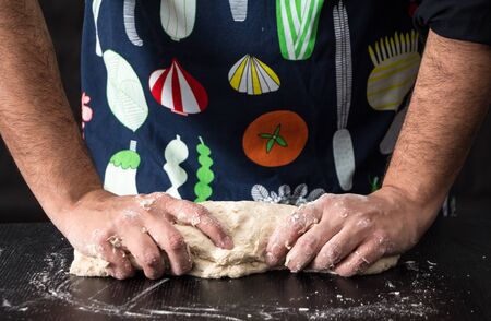 Male hands kneading dough, baking preparation closeup.の写真素材