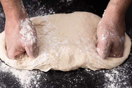 Male hands kneading dough, baking preparation closeup.の写真素材