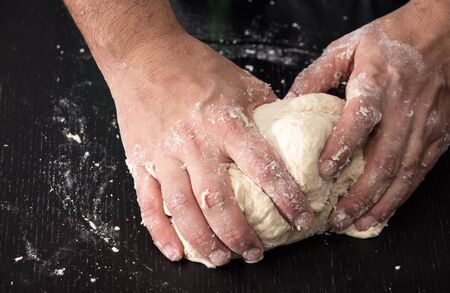 Male hands kneading dough, baking preparation closeup.の写真素材