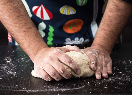 Male hands kneading dough, baking preparation closeup.の写真素材