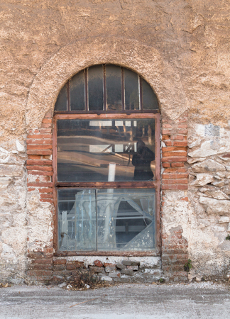 Old metal glass window, on weathered wall.の写真素材