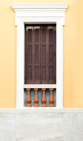 Wooden old retro style window with brown shutters, on clean painted wall background.の写真素材
