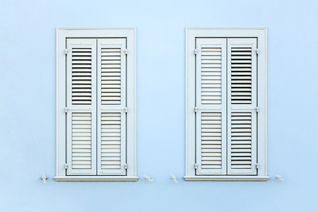 Wooden retro style windows with shutters, on clean painted wall background.の写真素材
