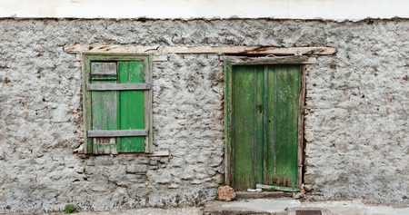 Weathered green painted door and window, on grungy concrete wall.の写真素材