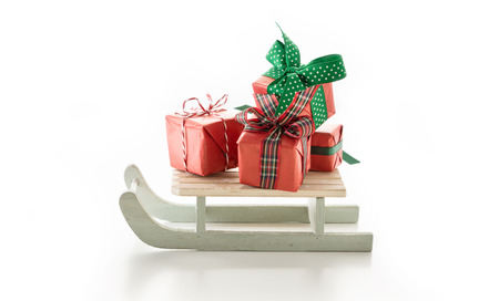 Wooden slide with present boxes decorated with seasonal ribbons, on white background.の写真素材