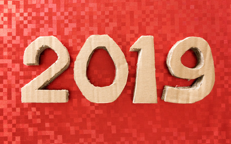 2019, handmade 3D numbers made of reused cardboard paper, on festive red background.の写真素材