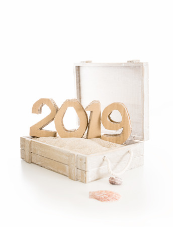 2019, handmade 3D numbers made of reused cardboard paper, in wooden chest with sand and on white background.の写真素材