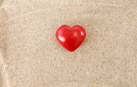 Red heart, on sandy background.の写真素材