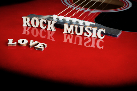 Words Love Rock Music with wooden letters, on reflecting surface of an acoustic guitar. Guitars bridge perspective. Creative background.の写真素材