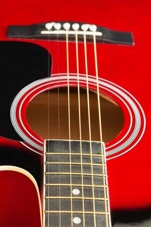 Closeup of a six stringed red acoustic guitar, from fingerboard side. Music entertainment background.の写真素材