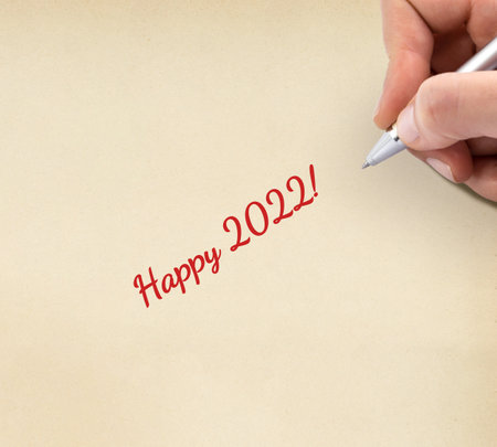 Hand writing "Happy 2022!" on yellow sheet of paper.の写真素材