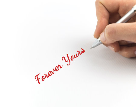 Hand writing "Forever Yours" on white sheet of paper.の写真素材