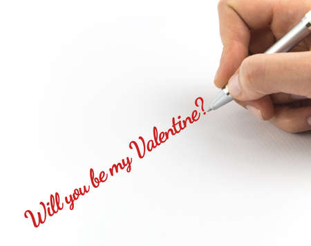 Hand writing "Will you be my Valentine?" on white sheet of paper.の写真素材