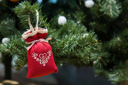 Christmas decorations, toys. Red rag bag hanging on a green Christmas tree.の写真素材