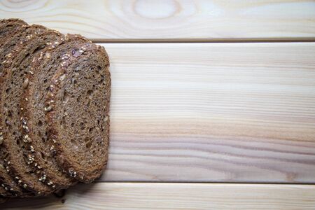 Slices of black bread with seeds lying on bright wooden backgroundの写真素材