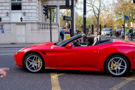 LONDON, UK - April 14, 2015: View of red Ferrari  in the street.  Woman drives a Ferrari