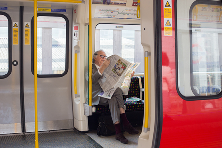 LONDON, UK - April 09, 2015: Senior man reading newspaper in the undergroundのeditorial素材