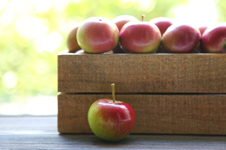 fresh red apples in wooden box on a green backgroundの写真素材