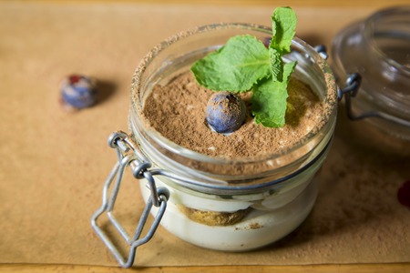 Cream dessert with a biscuit and cocoa in mason jar on a white backgroundの写真素材