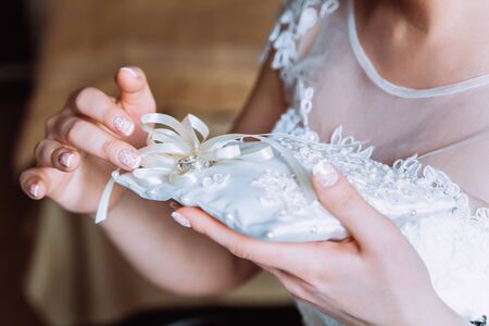 The bride is holding a pillow with wedding ringsの写真素材