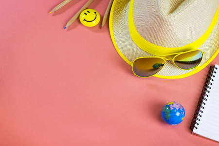 A yellow summer hat and bright mirror sunglasses. Must-have for travelling around the globe. An inspiring pink flatlay for planning a trip.の写真素材