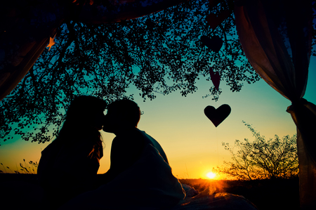 Silhouette of couple in love kissing at sunsetの写真素材
