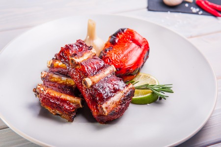 Close up Barbecue pork ribs and vegetables on the white plate on the wooden background with details. Selective focusの写真素材