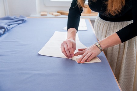 Seamstress hands on the work table with pattern. Style and design development and creating garment,...