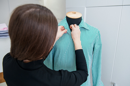 Female seamstress prepares a man's shirt to the fitting. Selective focusの写真素材