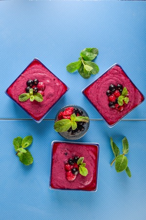Top view Several portions of berry smoothie on blue ceramic background. Well being, Healthy eating, Detox or Diet concept. Selective focus Flat layの写真素材