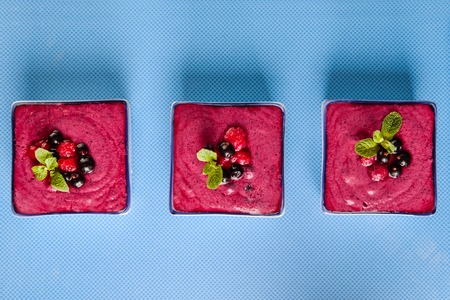 Top view Several portions of berry smoothie on blue ceramic background. Well being, Healthy eating, Detox or Diet concept. Selective focus Flat lay, space for text.の写真素材