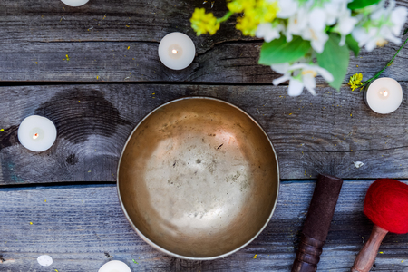 Tibetan singing bowl and special sticks, burning candles and vase with flowers on the dark wooden background, top view. Selective focus.の写真素材