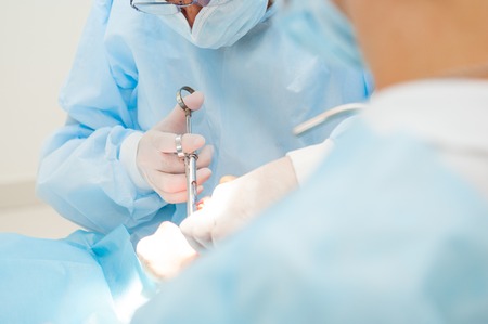 Close up dental surgery process - Implantation. Dentist surgeon with assistant in modern clinic. Stomatology and health care concept. selective focus. Space for text.の写真素材