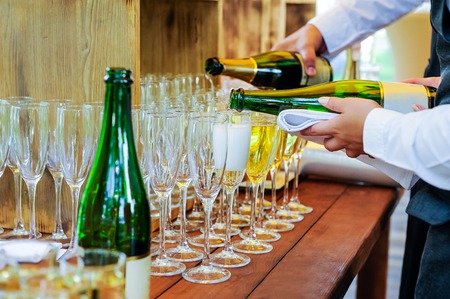 Waiter pouring personal serving Champagne in glasses. Catering service at events, corporate meeting, party, weddings. Selective focus, space for text.の写真素材