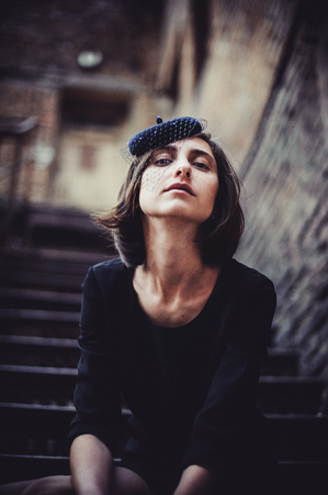 Retro Woman Portrait. Vintage Style Girl Wearing Old fashioned Hat. Romantic lady sitting on vintage forged staircase. Selective focus, space for textの写真素材
