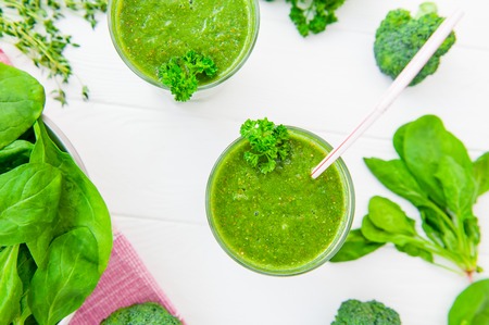 Fresh green Spinach smoothies in glass on the white wooden background. Healthy lifestyle concept....