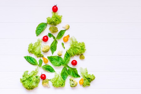 Healthy new year concept - Collection of fresh organic vegetables and greeens in form of christmas tree on white wooden background. Top view. Selective focus. space for text.の写真素材