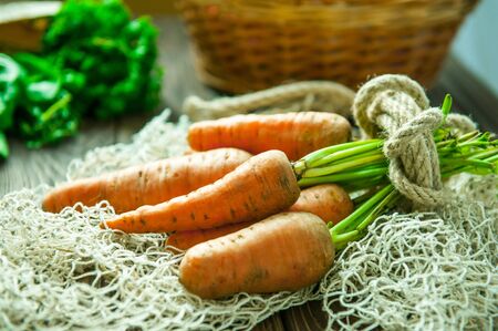 Bunch of Fresh organic dirty carrots and other purchased products from farm market on the wooden background. Vegetables. Healthy diet cooking concept. Vegetarian. Copy space for Text,. Selective focusの写真素材