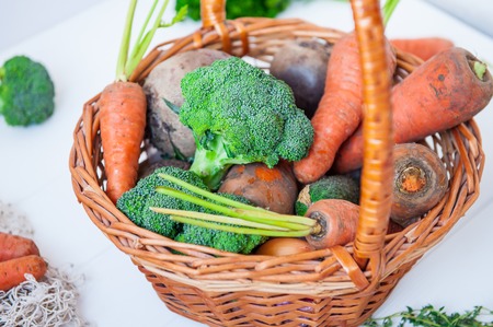 Straw Basket with garden Vegetables - fresh carrots, beets, broccoli, onions on the white wooden background. Farm Harvest. Food or Healthy diet concept.Vegetarian.Copy space for Text, .selective focus.の写真素材